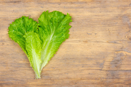 fresh green lettuce leaves on wooden background with copy space for recipesの写真素材