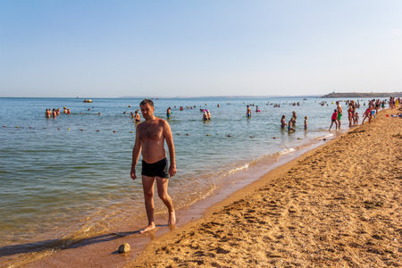 Kerch, Russia - 13 August 2019: vacationers and tourists swim in the Black Sea and sunbathe and relax on the beach on the beach on a summer dayのeditorial素材