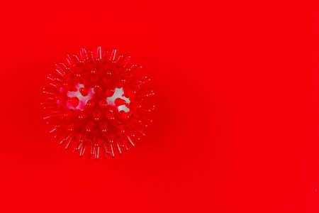 red medical massager in the form of a ball with spikes on a red background with a copy spaceの写真素材