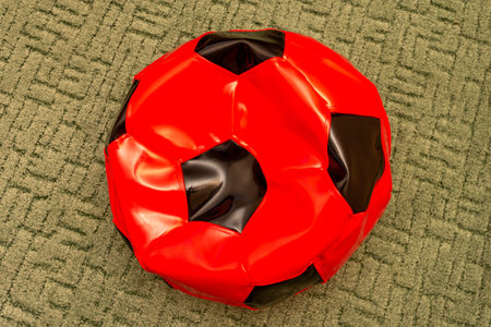 child beanbag chair in the form of a red football ball on the floor close-up