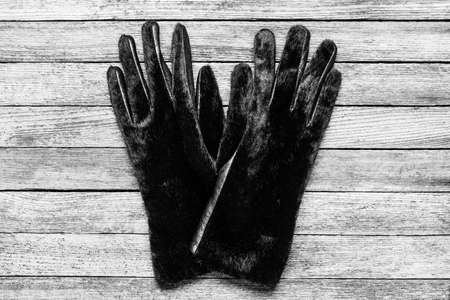 a pair of warm women's fur gloves on a wooden background close-up, top view black and white photoの写真素材
