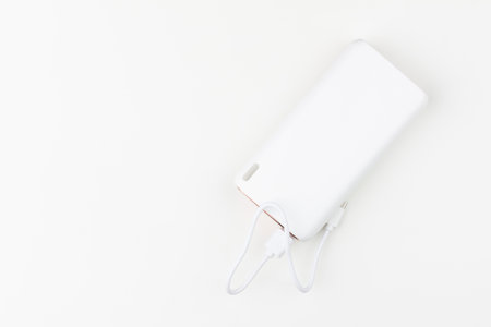 white power bank for charging smartphones and various digital devices on a white background close-up top view with copy spaceの写真素材