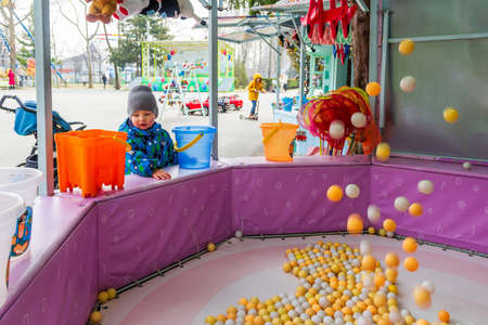a little boy walks in a recreation and entertainment park and plays in game attractionsの写真素材