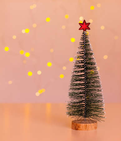 Christmas tree with a red star on a dark pink background with a bokeh of Christmas lights with a copy spaceの写真素材