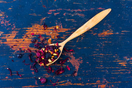 wooden spoon with dried flower berry tea on an old black wooden background top viewの写真素材