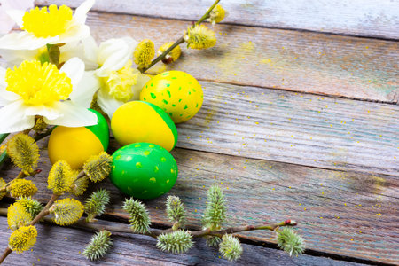 Easter composition of narcissus flowers, flowering willow twigs and Easter eggs with a pattern of...