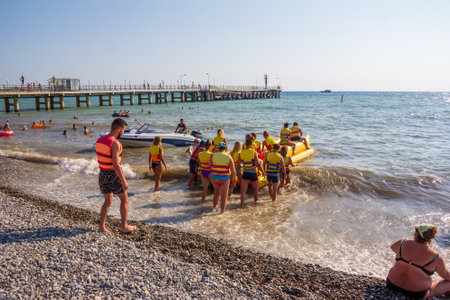 Sochi, Russia - August 22, 2018: vacationing tourists sit on an inflatable banana to ride on the sea waves on a hot summer dayのeditorial素材