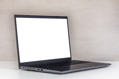 white mock-up on a laptop screen on a white table against a gray wall close-upの写真素材