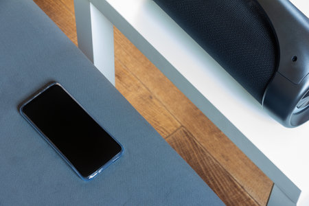 smartphone and black portable wireless speaker on the tableの写真素材