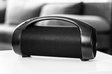 Portable wireless speaker on a table indoors against the background of a sofa, black and white photo, shallow depth of fieldの写真素材