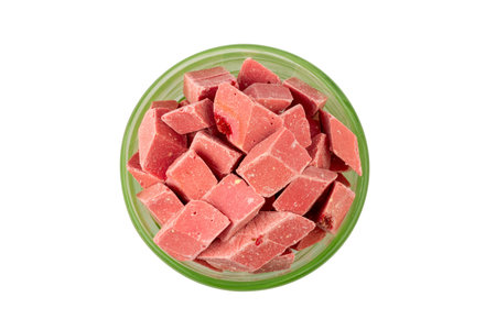pink pieces of Uzbek dairy strawberry halva in a green bowl isolated on a white background top view