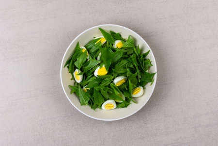 salad of fresh green spinach leaves and boiled quail eggs in a gray plate on a gray background top viewの写真素材