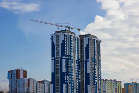 Crane and building construction site against blue skyの写真素材