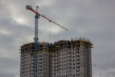 Crane and building construction site against blue sky.