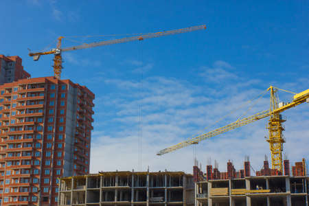 Crane and building construction site against blue skyの写真素材