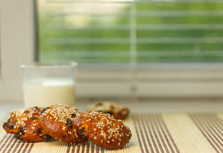 Biscuits on the table with sesame seeds, raisins and a glass of milk. On the window-sill. Healthy Eatingの写真素材