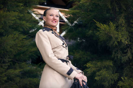 Happy girl in the coats at ulybvaetsja amid green treesの写真素材