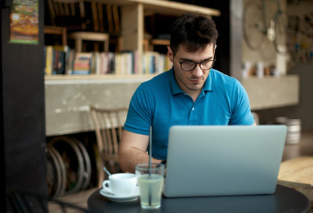 Young businessman drinking espresso coffee in the city cafe during lunch time and working on laptop