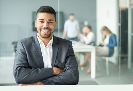 Smiling young businessman sitting in officeの写真素材