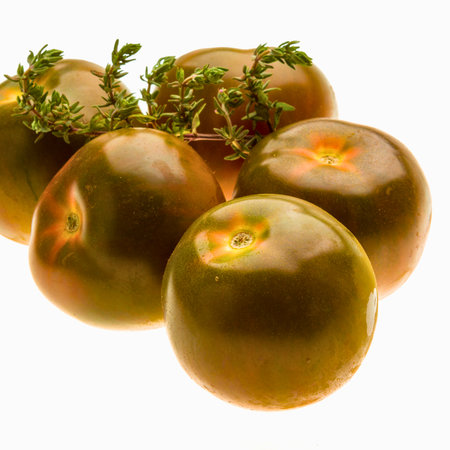 A cluster of ripe green tomatoes, some with green stems and leaves, arranged on a clean white surface.の写真素材