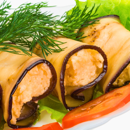 Close-up of golden-brown eggplant rolls stuffed with a creamy filling, garnished with fresh dill and lettuce.の写真素材