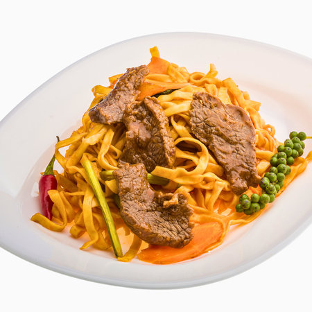 A close-up shot of a delicious stir-fried noodle dish featuring tender beef slices, vibrant vegetables, and a garnish of fresh green peppercorns.の写真素材