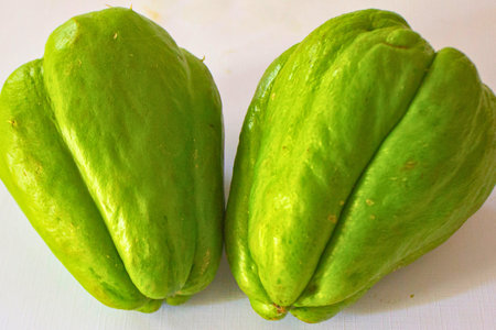 A close-up shot of two vibrant green chayote squash vegetables against a plain white background.の写真素材