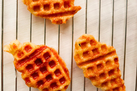 Three delicious golden brown waffles with crisp edges are artfully arranged on a white wooden background, creating a visually appealing breakfast scene.の写真素材