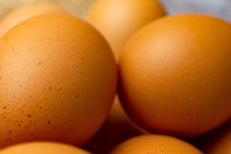 A close-up, detailed view of several brown chicken eggs, showcasing their speckled texture and oval...