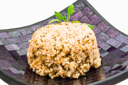 A close-up of a mound of fluffy rice seasoned with herbs, presented on a textured square plate with a white background.の写真素材