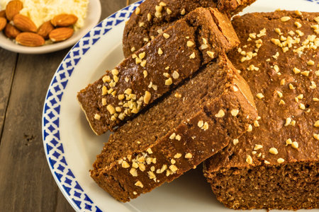 Close-up of sliced whole grain bread on a plate, sprinkled with sesame seeds, with almonds and...