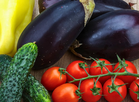Fresh, raw vegetables including eggplant, cucumber, cherry tomatoes on the vine, and yellow bell pepper. Ideal for healthy eating, cooking, and grocery.の写真素材