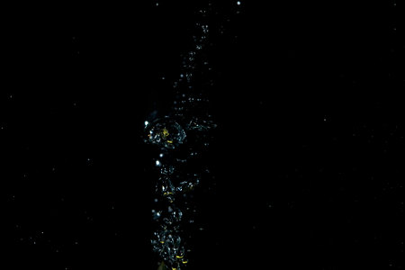 A stream of clear, transparent bubbles rises through a liquid medium. This dynamic visual creates an abstract and energetic effect, suitable for various design projects.の写真素材