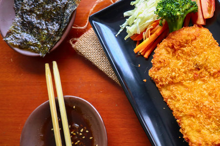 Crispy golden fried katsu fillet, fresh vegetable salad, savory dipping sauce, chopsticks, and roasted seaweed. A delicious and healthy Asian meal!の写真素材