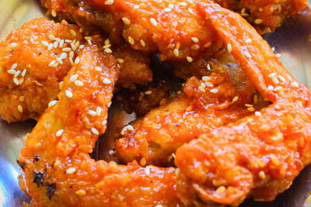 Close-up of crispy, sticky chicken wings generously coated in a vibrant, savory and sweet, spicy honey-sesame glaze. Ideal for menus or food blogs.の写真素材