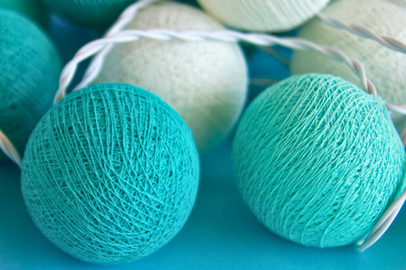Macro shot of decorative string lights featuring teal and white textured spherical bulbs, creating a festive and cozy atmosphere.の写真素材