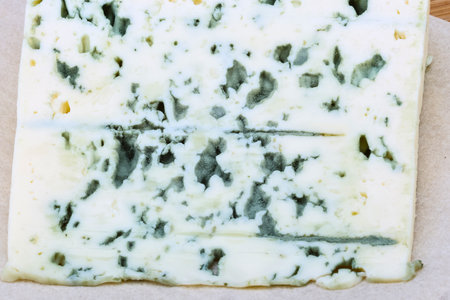 A detailed view of a block of blue cheese, showcasing its creamy texture and characteristic blue-green mold veins.の写真素材