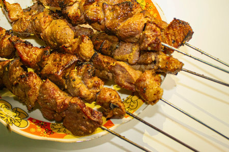 A close-up shot of perfectly grilled chicken skewers, glistening with marinade and ready to be served, piled high on a colorful plate.の写真素材