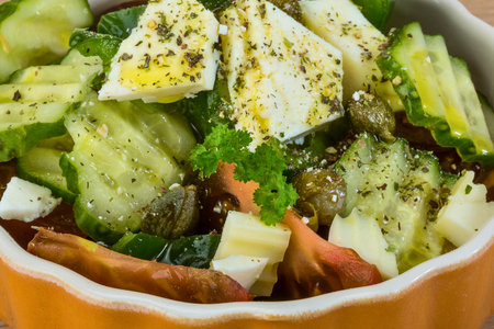 A vibrant and healthy Greek salad featuring crisp cucumber, feta cheese, and fresh greens, seasoned with herbs.の写真素材