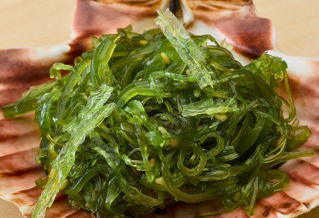 A vibrant mound of fresh green seaweed salad is artfully arranged on a decorative, light-colored plate, suggesting a healthy and flavorful dish.の写真素材