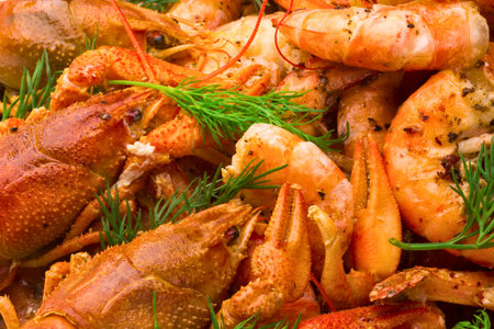 A close-up, overhead view of a vibrant seafood assortment featuring cooked shrimp and crayfish, garnished with fresh green herbs.の写真素材