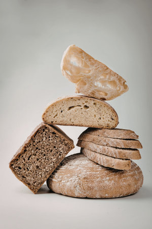 A collection of various types of artisan bread, including sourdough, rye, and baguette, displayed in...