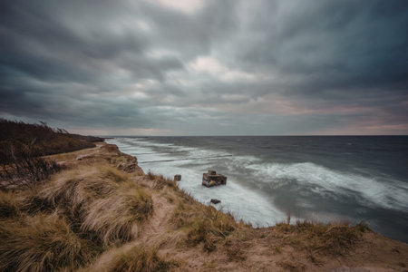 A dramatic coastal scene with a cloudy sky, waves crashing against the shore, and rugged cliffs...