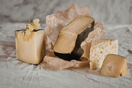 A variety of artisanal cheeses displayed on crinkled paper, showcasing different textures and...