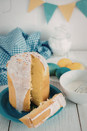 A close-up image of a sliced cake with pink icing and colorful sprinkles on a blue plate,...