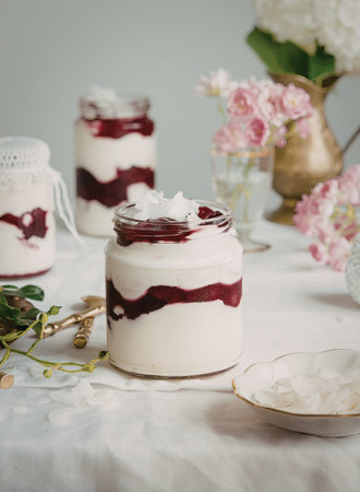A close-up of a beautifully layered yogurt parfait with a berry compote swirl, served in a glass...