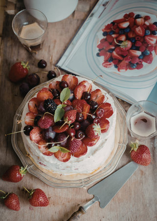 A beautifully decorated cake topped with an assortment of fresh fruits, including strawberries,...