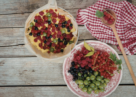 A rustic wooden table displays two bowls filled with a variety of fresh berries, including...