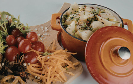 A vibrant display of fresh vegetables and herbs arranged on a wooden cutting board, accompanied by a red pot with a lid.の写真素材