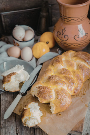 A loaf of freshly baked bread is displayed on a wooden board, accompanied by a knife with butter,...